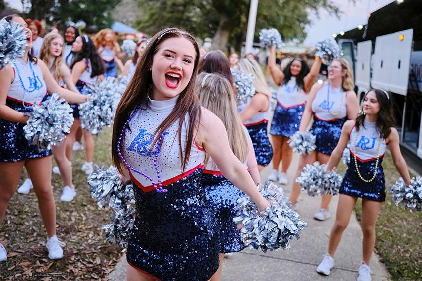 Cheerleader smiling with her pom poms during Mardi Gras Celebration